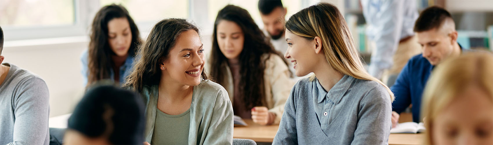 A group of college students sitting at rows of desks in a classroom setting